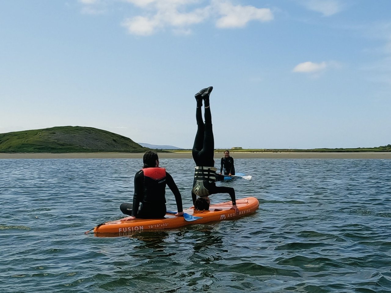 person doing head stand on paddle board