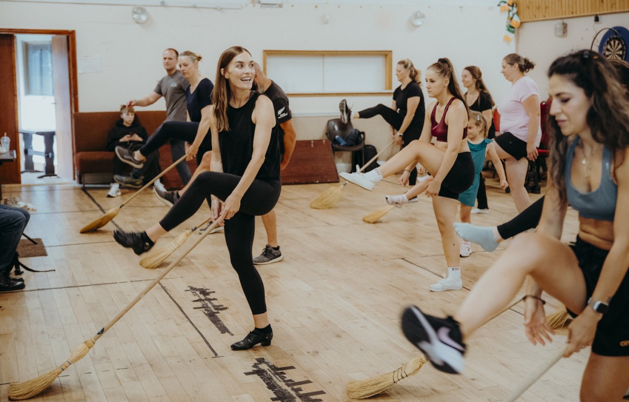 Class of people learning how to dance, throwing their leg over a brush